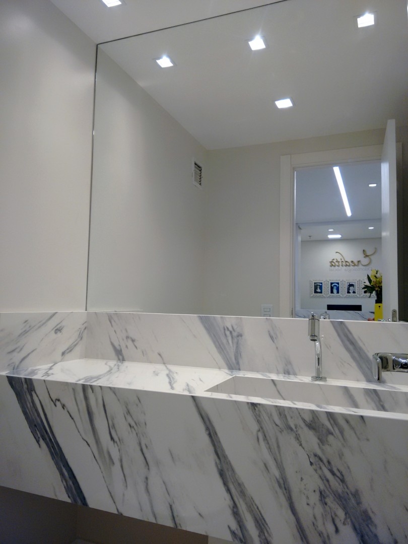 clinica odontologica tons neutros iluminação led  - lavabo com cuba moldada em silestone padrão carrara